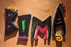 Colorful handmade fabric letters spelling "DVC" laid out on a wooden surface, featuring Disney-themed decorative elements and stitching.