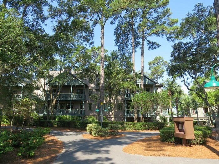 Disney Vacation Club resort buildings surrounded by lush trees and landscaping with a curved walkway leading to the entrance.