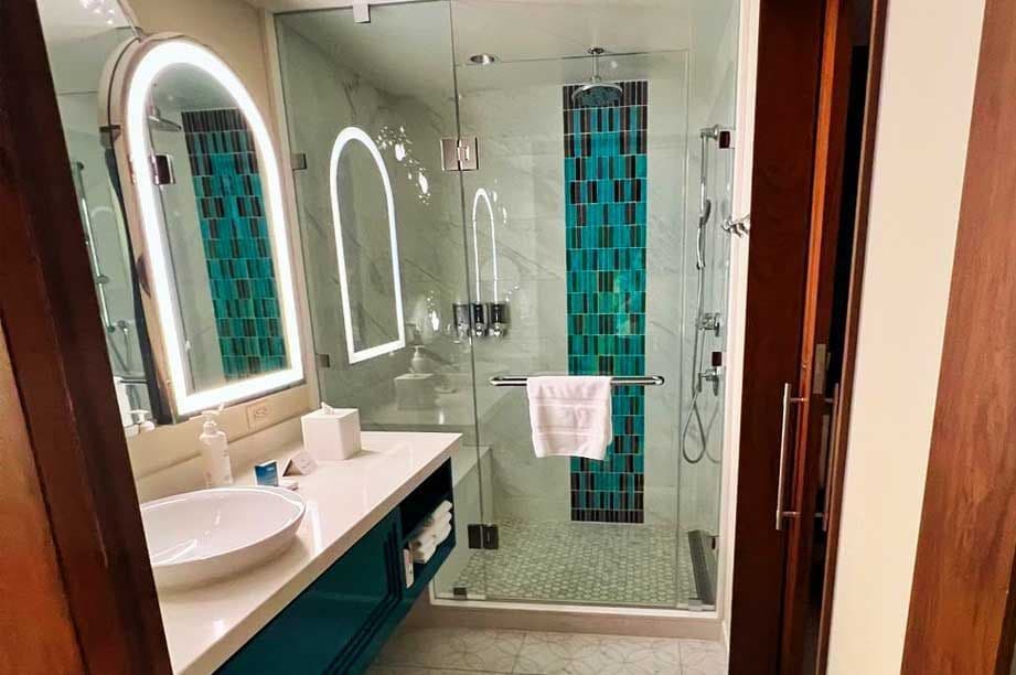 VDH Bathroom with backlit mirror and beautiful glass shower, green tile