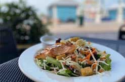 Fresh salad with grilled chicken, mixed greens, and vegetables served on white plate at outdoor Disney resort restaurant