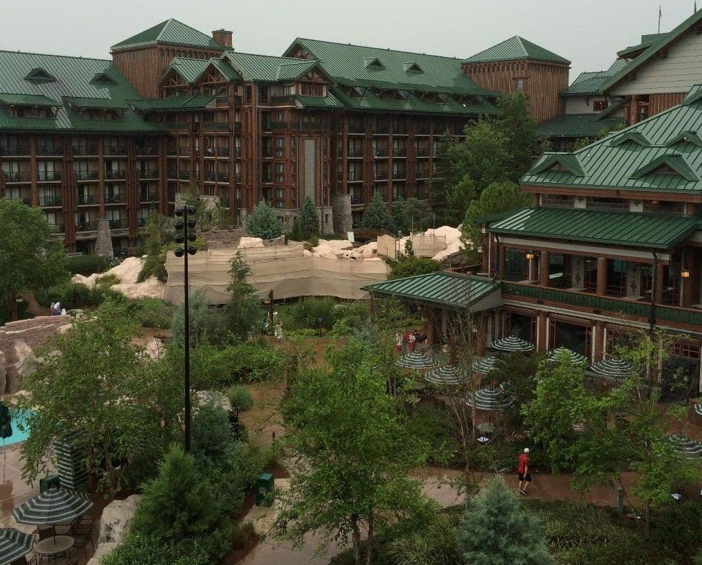 Large rustic resort hotel with green copper roofs and wooden architecture surrounded by lush landscaping and pathways.