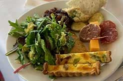 Plate with mixed greens salad, sliced salami, cheese, crackers and bread at Disney Vacation Club resort dining venue.